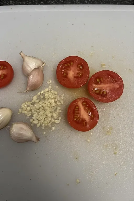 Alt text: Minced garlic and halved cherry tomatoes prepped for zucchini noodles with garlic butter