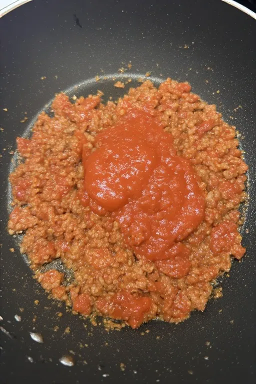 Ground turkey filling with tomato sauce simmering in skillet for stuffed peppers