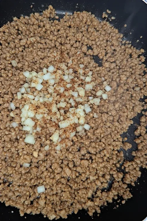 Onion garlic and spices added to ground turkey for stuffed pepper filling