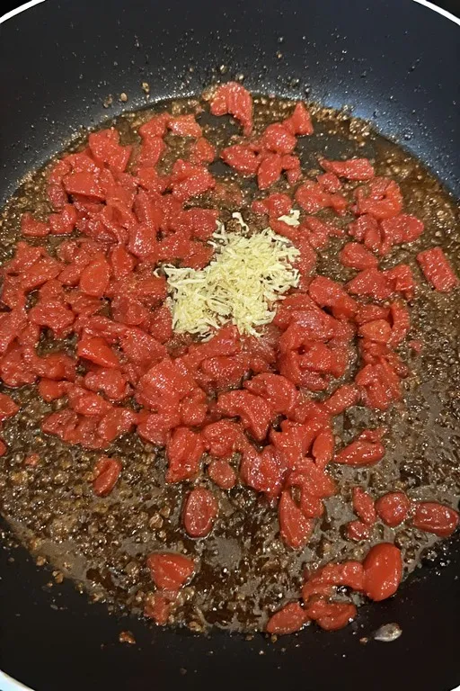 Garlic and sun-dried tomatoes sautéing in skillet for marry me chicken sauce