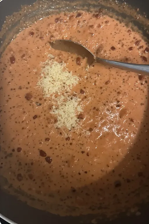 Parmesan stirred into creamy marry me chicken sauce in skillet
