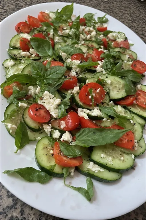 Fresh basil torn and scattered over cucumber caprese salad