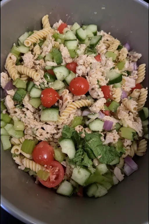 Chicken pasta salad ingredients combined in a large bowl before dressing