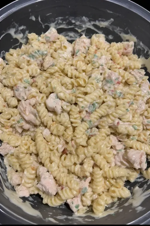  Creamy chicken pasta salad being tossed with homemade dressing in a bowl