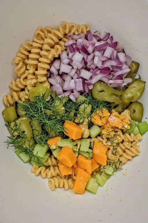 Dill pickle pasta salad ingredients combined in a large bowl before tossing