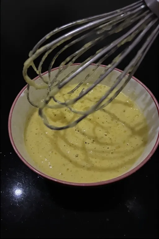 Homemade lemon dressing for orzo pasta salad being whisked in a bowl