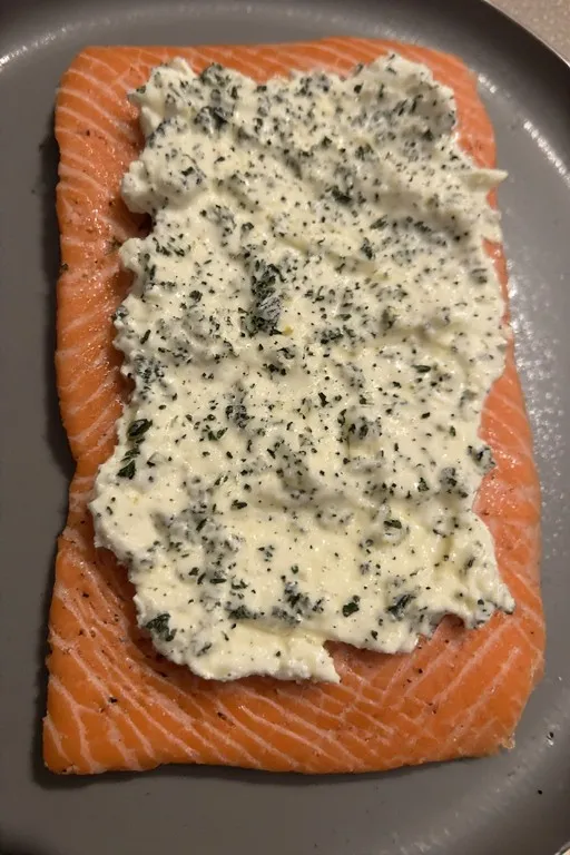 Boursin cheese spread on raw salmon fillet before baking