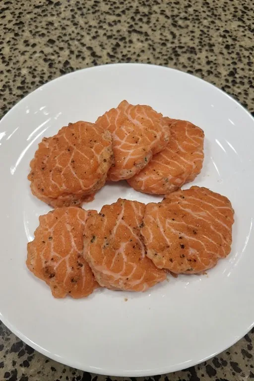 Formed raw canned salmon patties on plate before pan frying