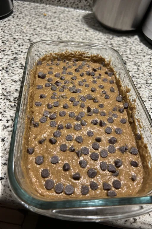 Chocolate zucchini bread batter in loaf pan with chocolate chips on top before baking