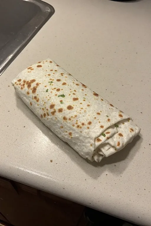 Freezer breakfast burrito being wrapped tightly before freezing
