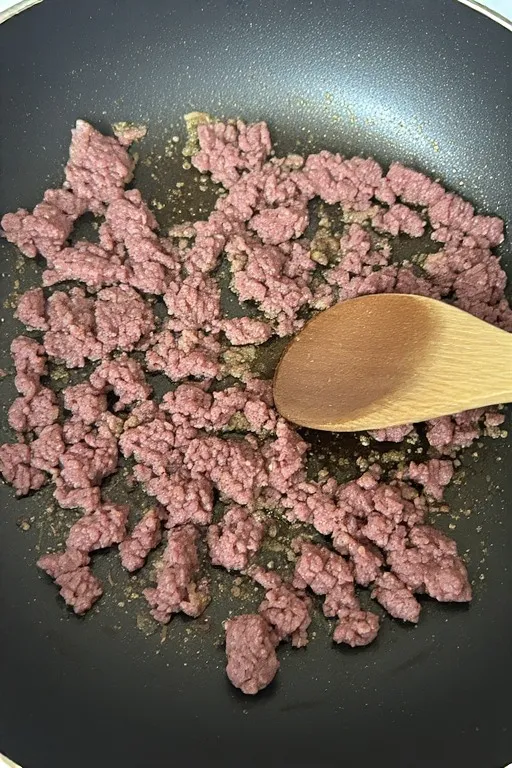 Ground beef browning in skillet for keto zucchini boat filling