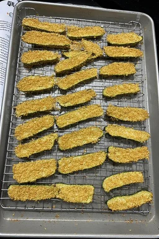 Coated keto zucchini fries arranged in single layer on wire rack ready to bake
