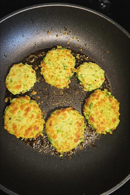 Frying keto zucchini fritters in skillet until golden brown