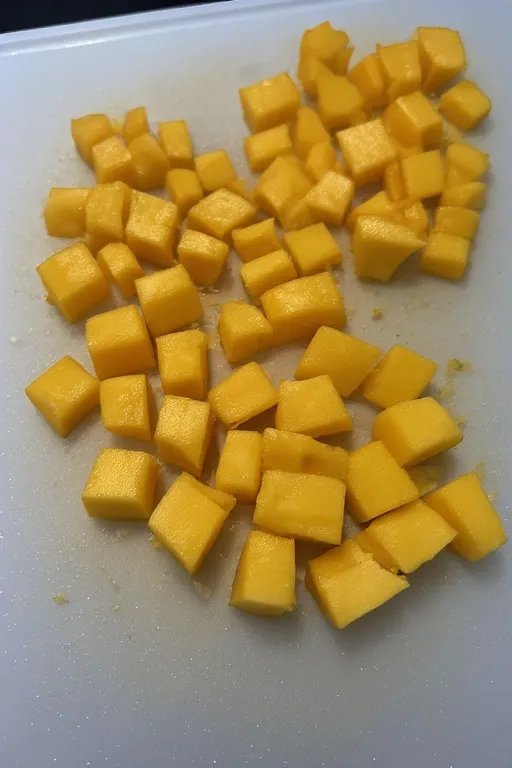 Ripe mango diced into small cubes on cutting board for fresh mango salsa recipe