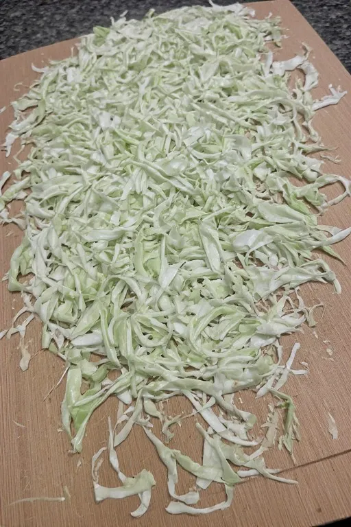 Finely shredded green cabbage on cutting board for mango slaw recipe