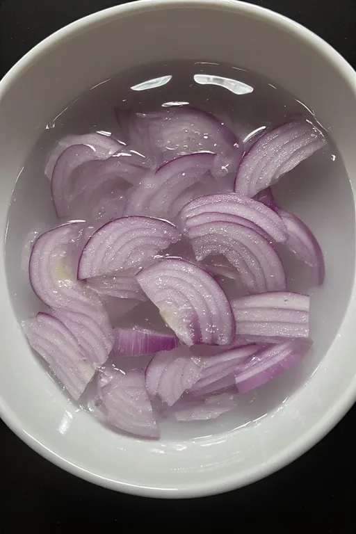 Paper-thin red onion slices soaking for mango slaw dressing