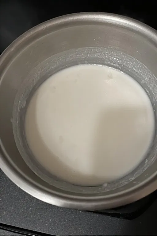 Coconut milk and sugar mixture warming in saucepan for sticky rice