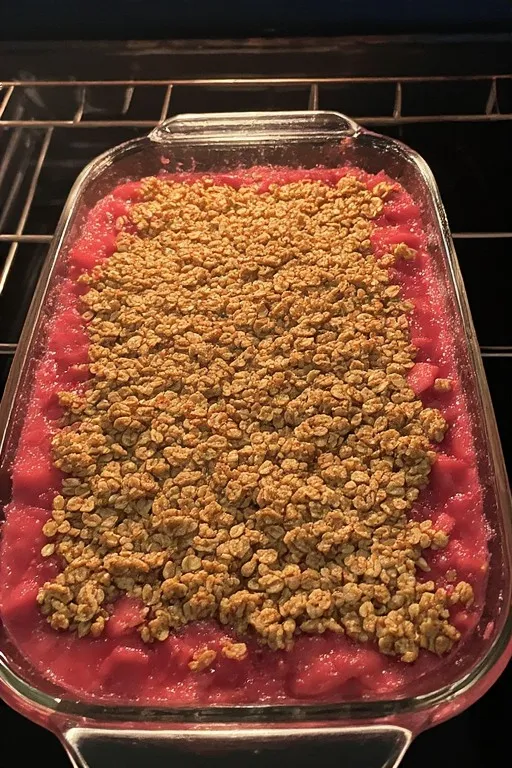 Rhubarb crisp baking in oven with golden topping and bubbling filling