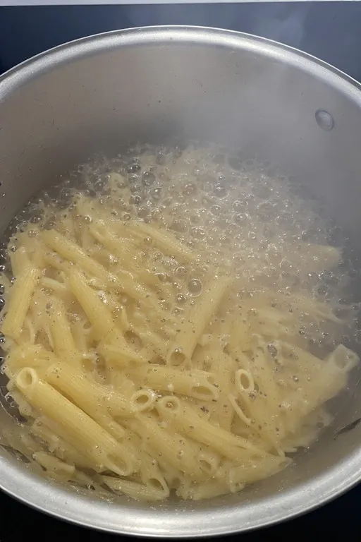 Penne pasta boiling in pot for tomato zucchini pasta recipe