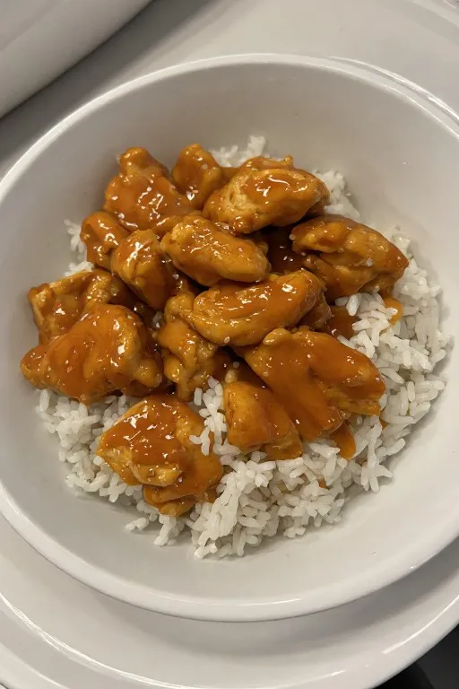 Crock pot apricot chicken plated over rice with thick glossy sauce and parsley