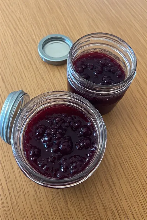 Homemade blackberry jam in jars on wooden surface ready to store
