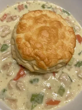 Crock pot chicken pot pie in bowl with golden biscuit on top ready to serve