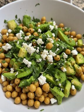 Chickpea feta avocado salad in bowl with lemon herb dressing ready to serve