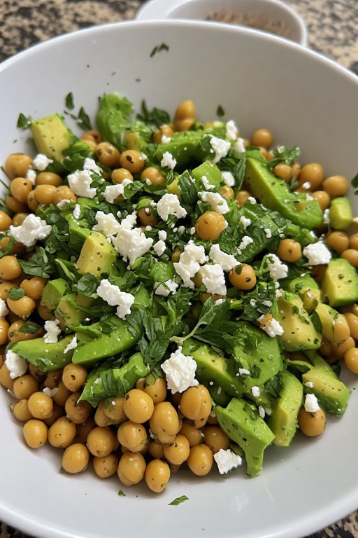 Chickpea feta avocado salad in bowl with lemon herb dressing ready to serve