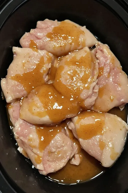 Raw chicken thighs in crockpot with teriyaki sauce ready to cook for crockpot teriyaki chicken recipe