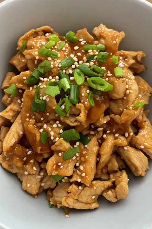 hredded crockpot teriyaki chicken coated in glossy sauce with sesame seeds