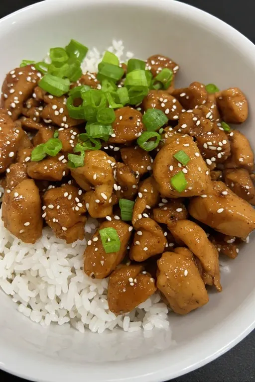 Dump and go crockpot teriyaki chicken served over rice with sesame seeds and green onions