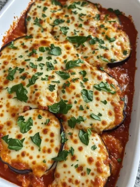 Eggplant parmesan fresh from oven in baking dish with golden bubbly mozzarella and fresh basil