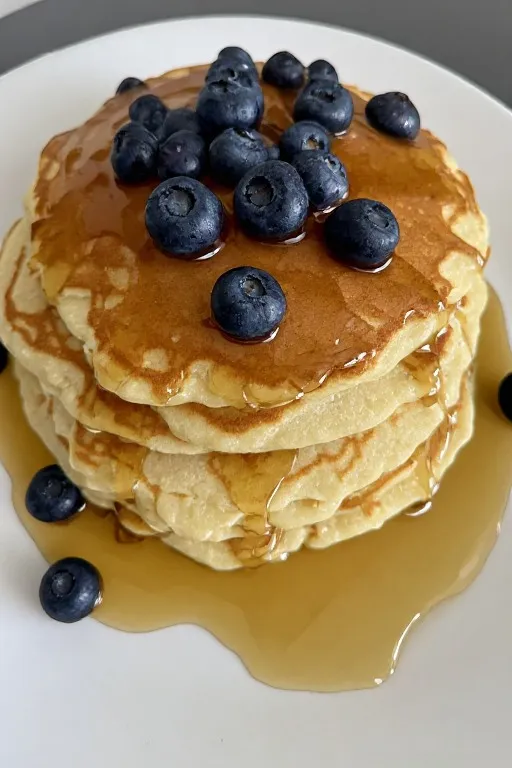 Fluffy pancake recipe with fresh blueberries and maple syrup on a plate