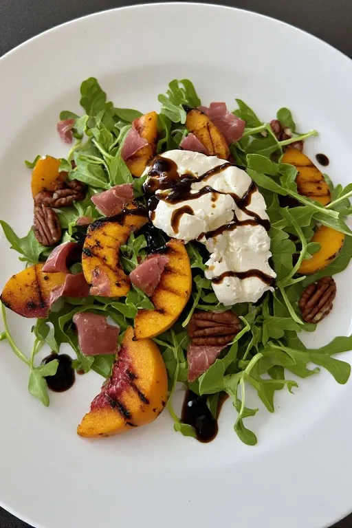 Grilled peach salad with burrata prosciutto arugula and balsamic honey dressing on plate