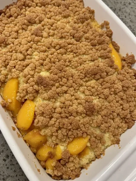Peach dump cake in baking dish fresh from oven with golden crumble top