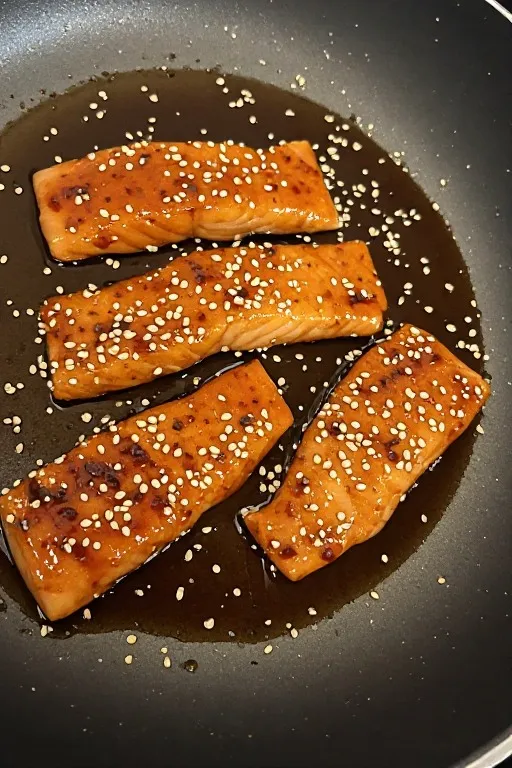 Salmon teriyaki fillets with glossy caramelized teriyaki glaze in pan