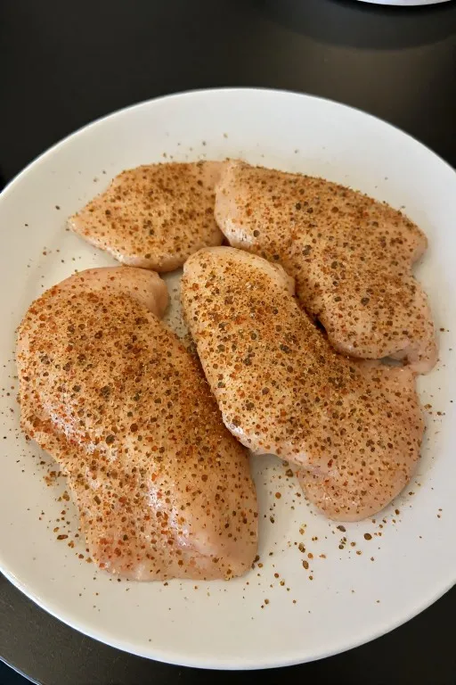 Seasoned chicken breasts ready to sear for creamy smothered chicken and rice recipe