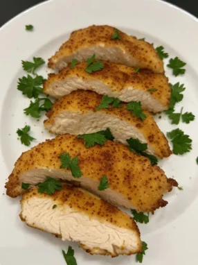 Air fryer chicken breast sliced on white plate showing juicy interior and golden seasoning