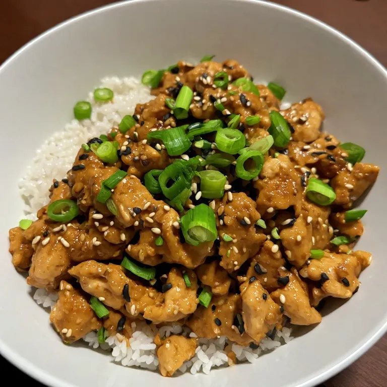Healthy chicken stir fry served over rice with sesame seeds and green onion