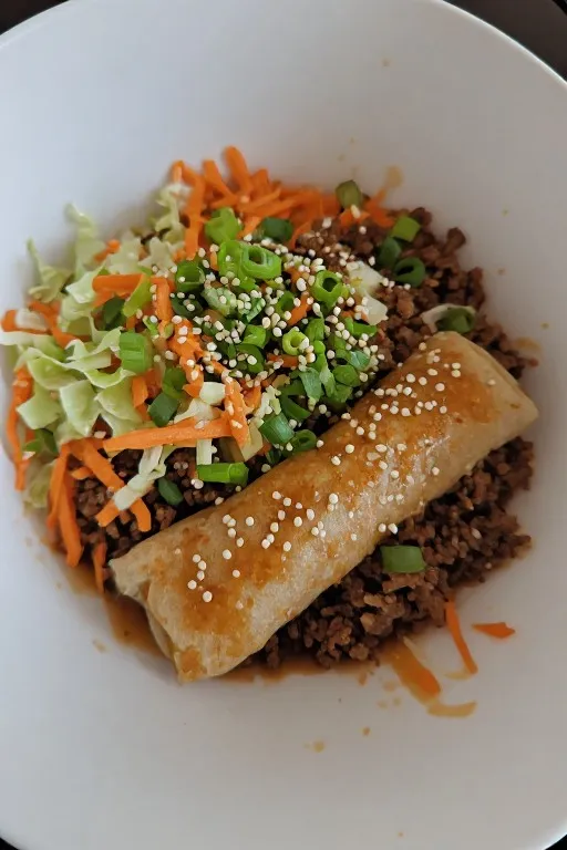 Egg roll in a bowl served over jasmine rice with green onions sesame seeds and sriracha
