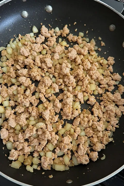 Ground turkey browning in skillet with onion and garlic for ground turkey skillet recipe