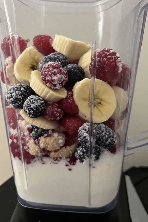 Blender with frozen fruit, banana, and yogurt before blending