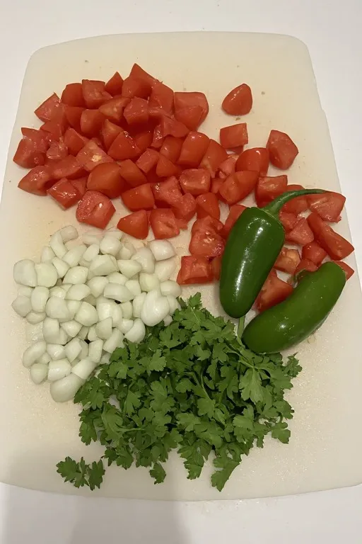 Diced tomatoes onion jalapeño and cilantro on cutting board before mixing