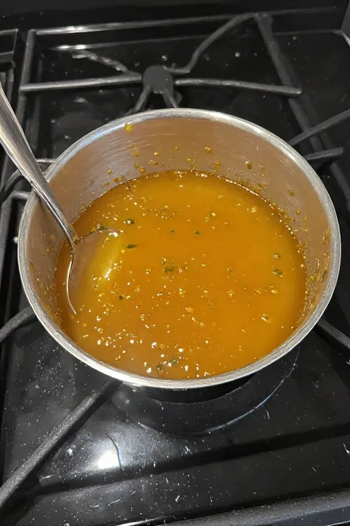 Jalapeño peach glaze simmering in saucepan for chicken skewers recipe