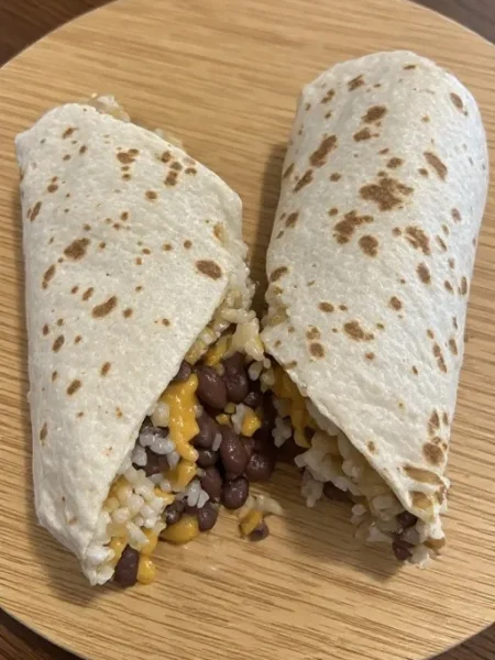 Bean burrito sliced in half showing beans rice and cheese inside