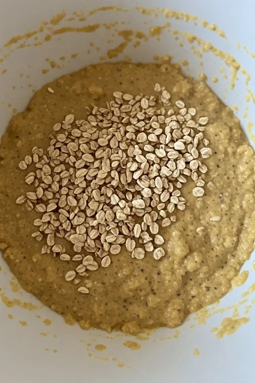 Banana oatmeal muffin batter with oats and mashed banana in bowl