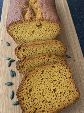 Sliced pumpkin bread on wooden board showing moist crumb