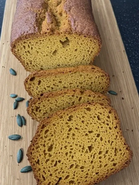 Sliced pumpkin bread on wooden board showing moist crumb