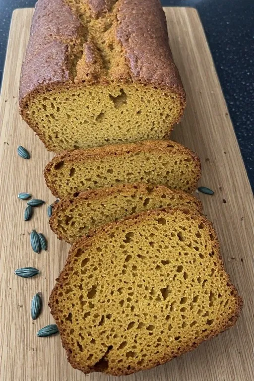 Sliced pumpkin bread on wooden board showing moist crumb