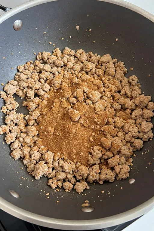 Ground turkey browning with taco seasoning in skillet